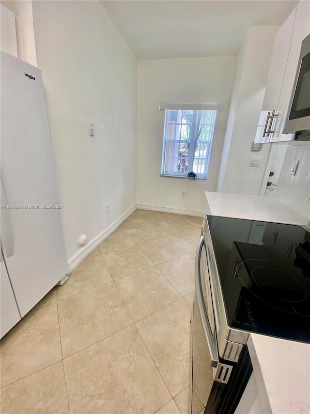 kitchen featuring appliances with stainless steel finishes, light tile patterned flooring, and white cabinets