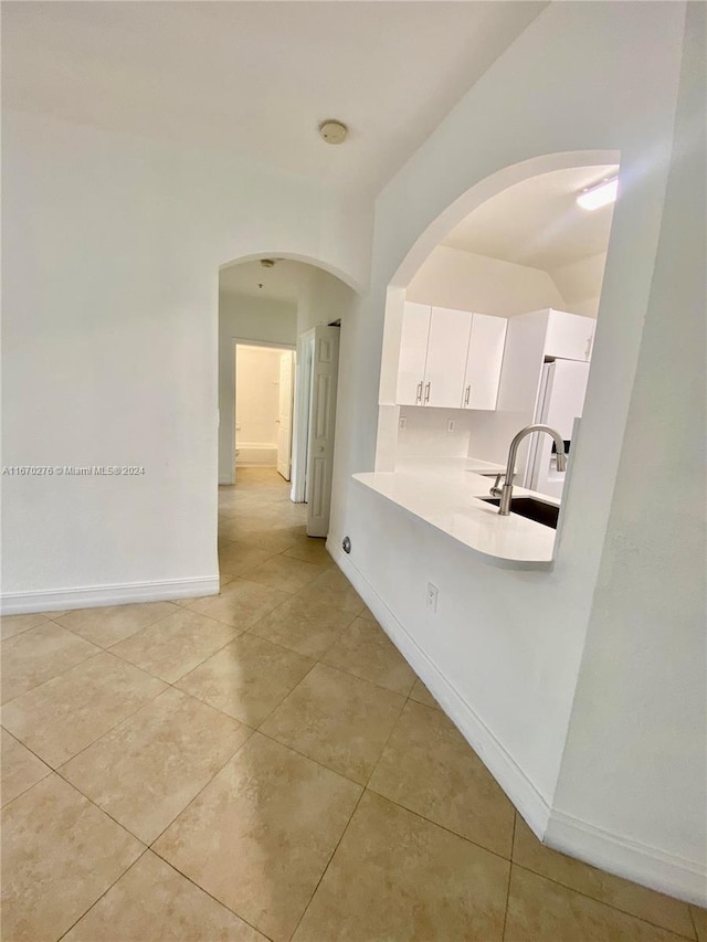 interior space with light tile patterned flooring, sink, and white cabinets