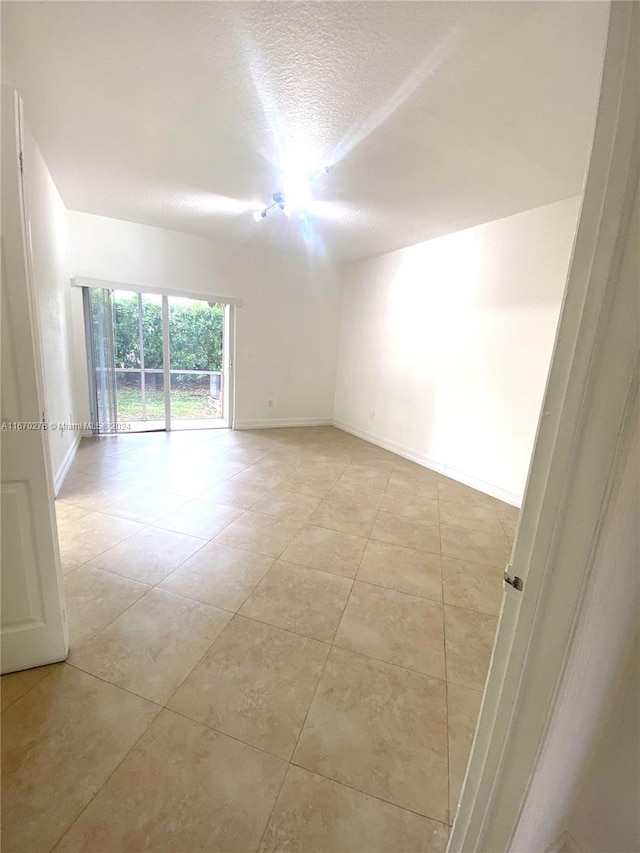 empty room with a textured ceiling and light tile patterned floors