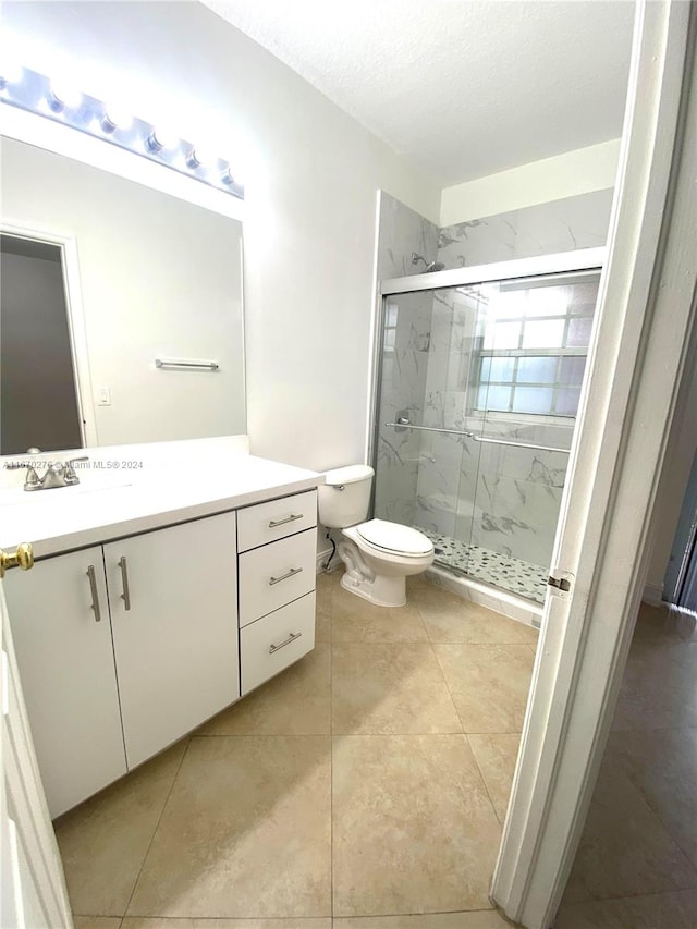 bathroom with a textured ceiling, a shower with shower door, vanity, and toilet