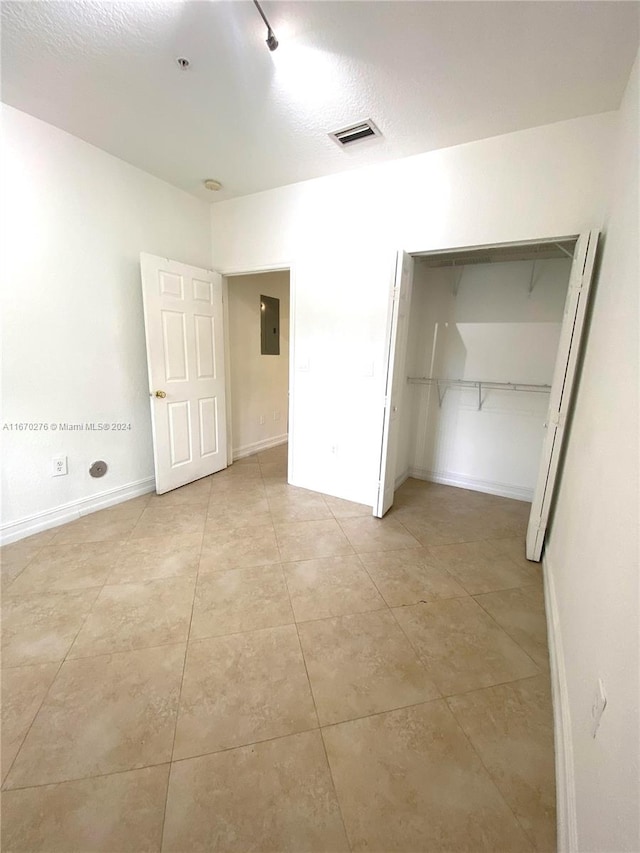 unfurnished bedroom with a closet, electric panel, light tile patterned flooring, and a textured ceiling