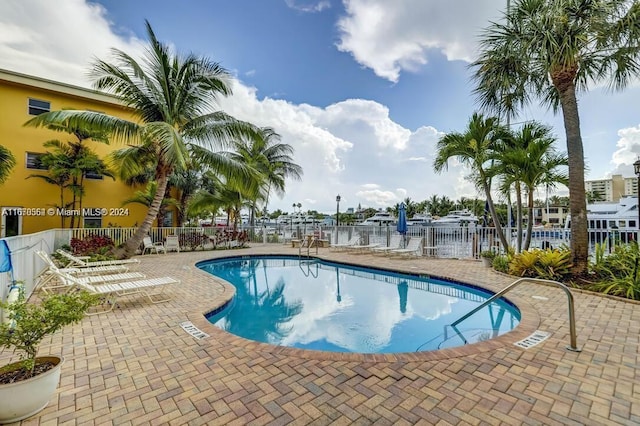 view of swimming pool with a water view and a patio area