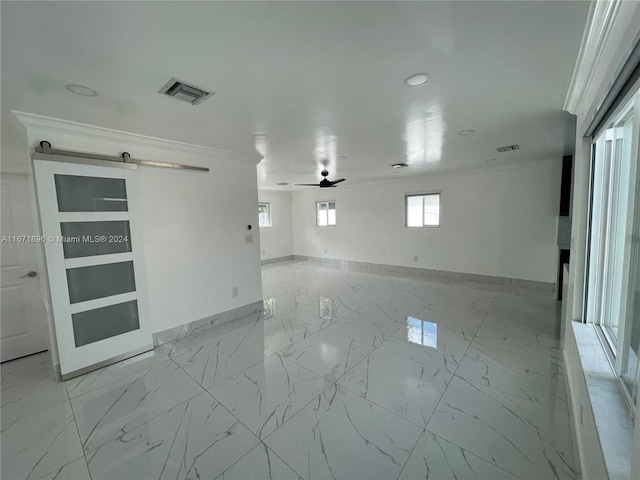 unfurnished room featuring a barn door, ceiling fan, and ornamental molding