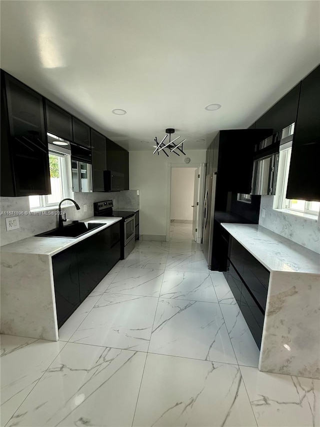 kitchen with decorative backsplash, sink, stainless steel appliances, and an inviting chandelier