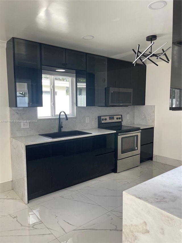 kitchen with backsplash, sink, a notable chandelier, and appliances with stainless steel finishes