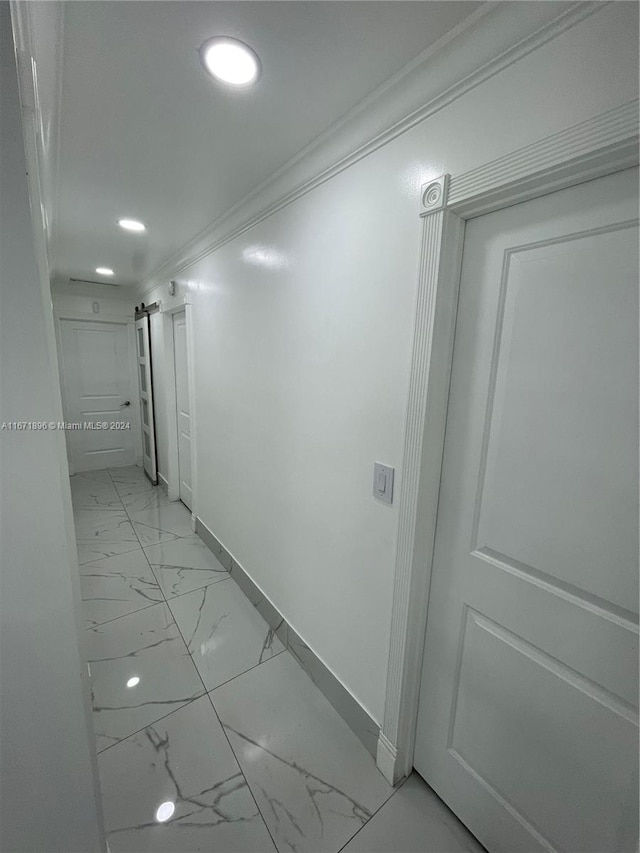 hallway featuring a barn door and crown molding