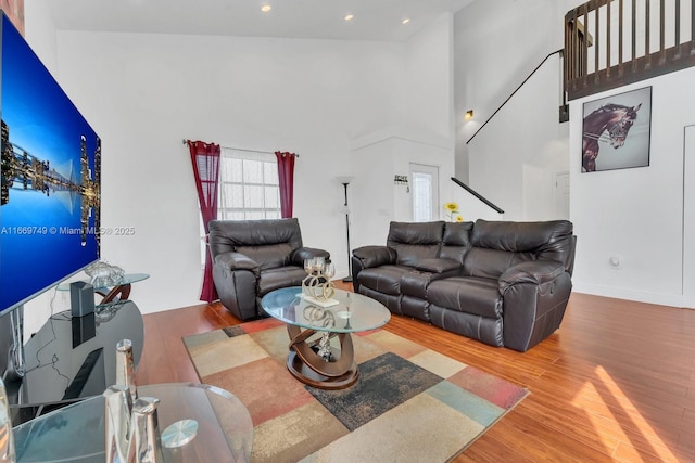 living room featuring a towering ceiling and wood-type flooring