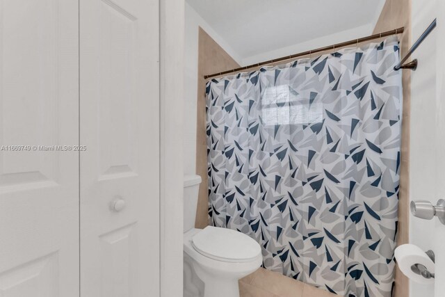 bathroom with a shower with shower curtain, tile patterned flooring, and toilet