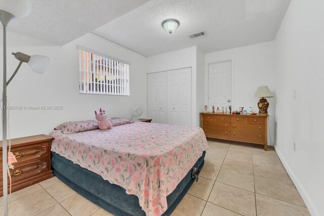 tiled bedroom with a textured ceiling and a closet