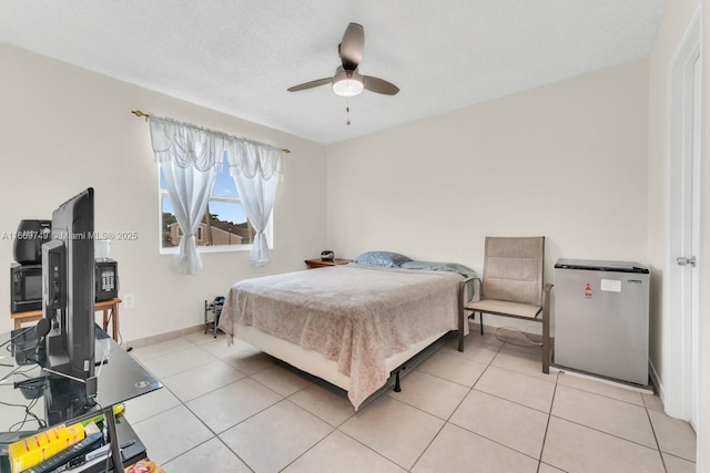 bedroom with ceiling fan, light tile patterned floors, and a textured ceiling