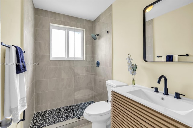 bathroom featuring toilet, vanity, and a tile shower