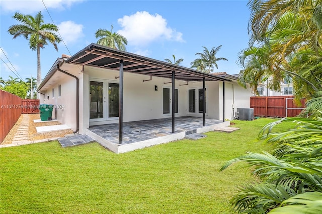 back of house featuring central air condition unit, a lawn, french doors, and a patio area