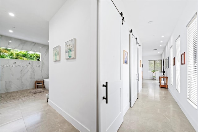 hall featuring a barn door and tile walls