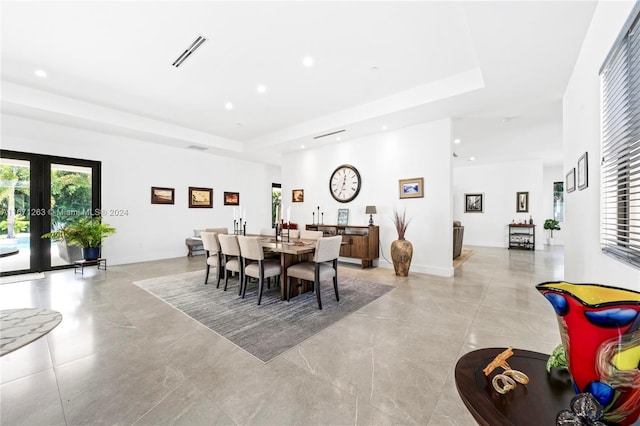 dining space with french doors and a tray ceiling