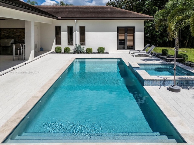 view of swimming pool featuring an in ground hot tub and a patio