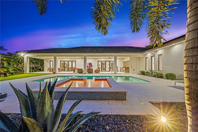 pool at dusk with an in ground hot tub, a patio area, and french doors