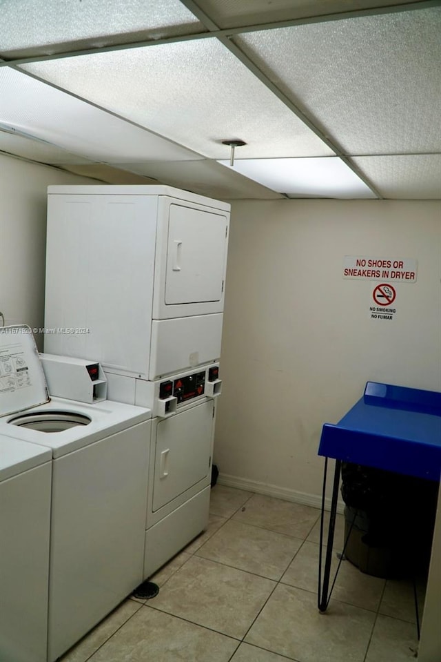 washroom with stacked washer and dryer and light tile patterned floors