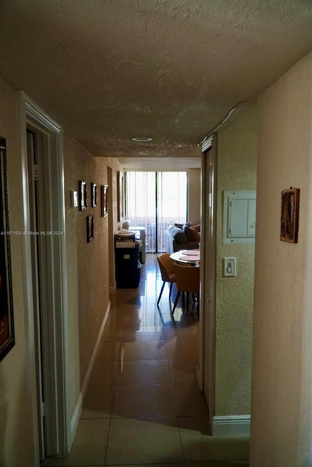 corridor with a textured ceiling and tile patterned floors