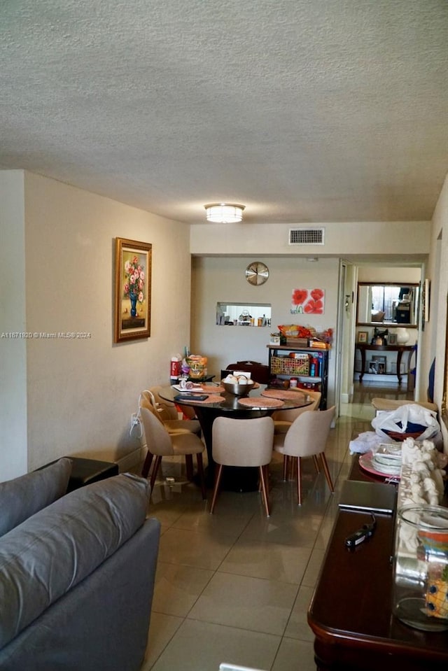 dining space featuring a textured ceiling and light tile patterned floors