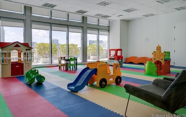 recreation room with a drop ceiling and a wealth of natural light