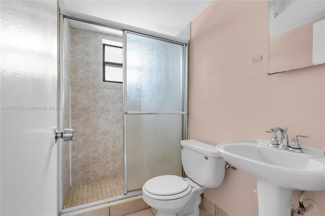 bathroom with a shower with door, sink, and toilet