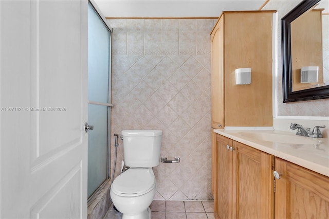 bathroom featuring tile patterned floors, toilet, tile walls, vanity, and a shower with door