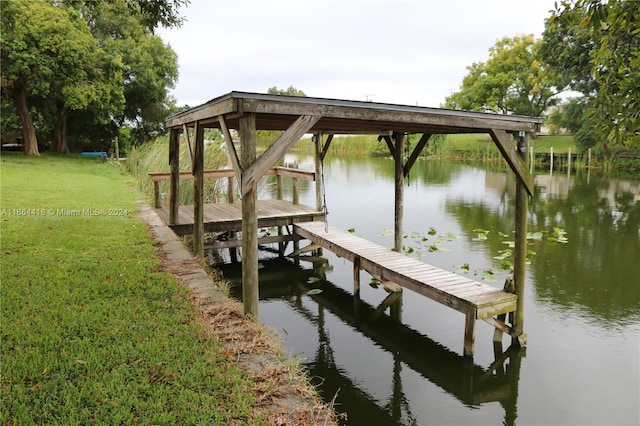 dock area with a water view and a lawn