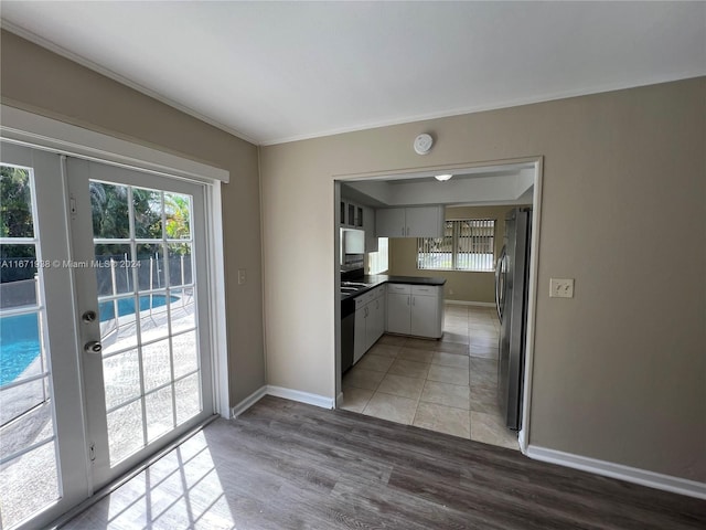 kitchen with ornamental molding, stainless steel refrigerator, light hardwood / wood-style floors, and white cabinetry