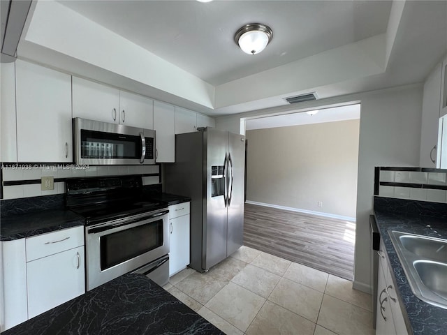 kitchen with light hardwood / wood-style floors, sink, white cabinets, backsplash, and appliances with stainless steel finishes