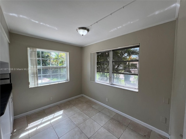 spare room featuring ornamental molding and light tile patterned floors