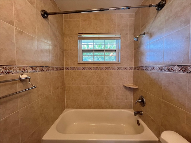 bathroom featuring toilet and tiled shower / bath