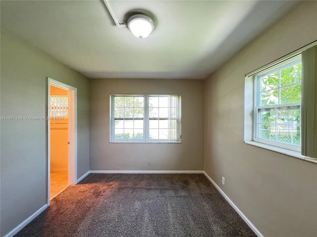 unfurnished bedroom with dark carpet, a closet, and multiple windows