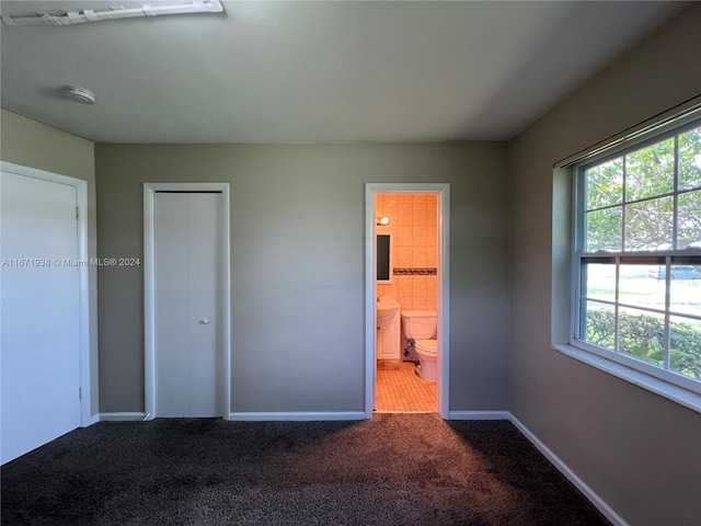 unfurnished bedroom featuring a closet, connected bathroom, and carpet flooring