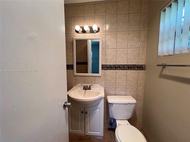 bathroom with tile walls, vanity, and toilet