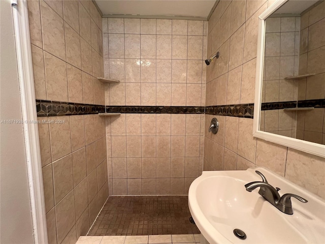 bathroom featuring tile walls, tiled shower, sink, and tile patterned floors