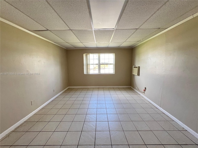 spare room featuring crown molding, a paneled ceiling, light tile patterned flooring, and an AC wall unit