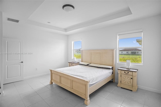 bedroom with a raised ceiling and light tile patterned floors