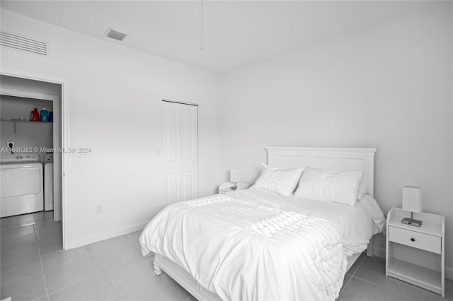 tiled bedroom with washing machine and clothes dryer and a closet