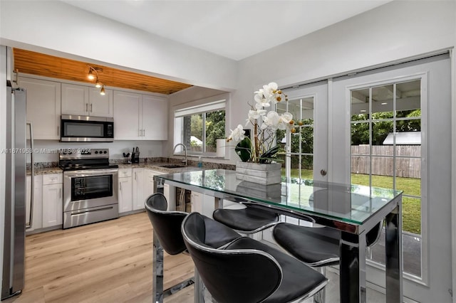 kitchen with stainless steel appliances, light hardwood / wood-style flooring, white cabinets, and sink