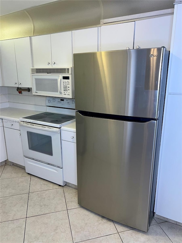 kitchen with white cabinets, white appliances, light tile patterned floors, and backsplash