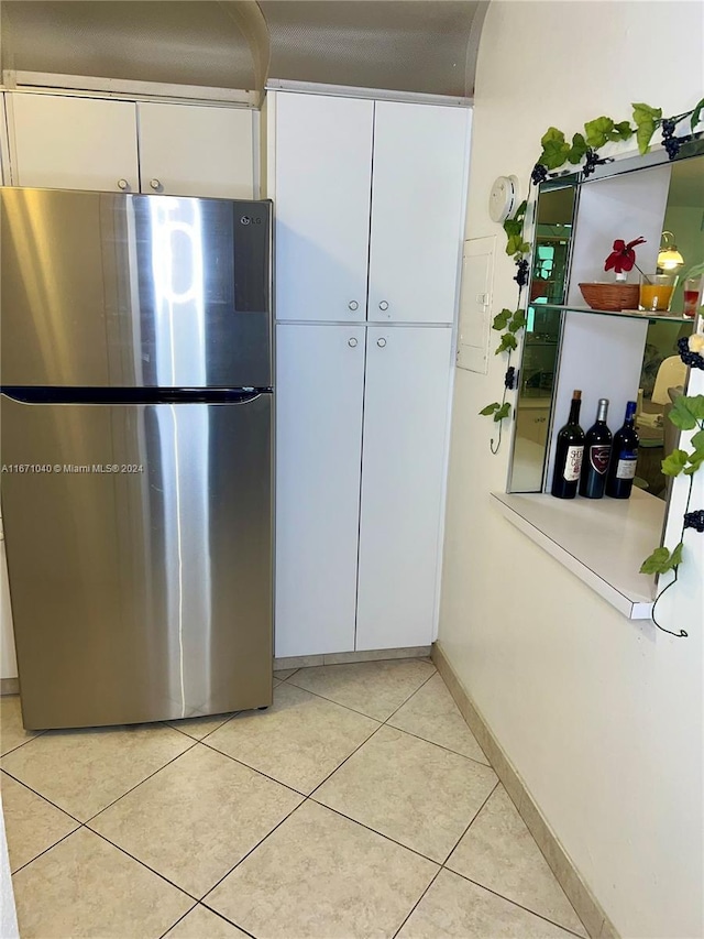 kitchen with white cabinetry, light tile patterned floors, and stainless steel refrigerator