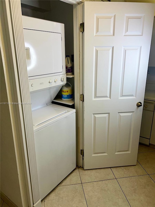 laundry room with light tile patterned flooring and stacked washer and dryer