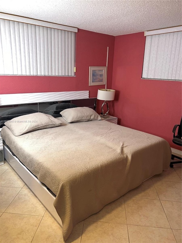 bedroom with a textured ceiling and light tile patterned floors