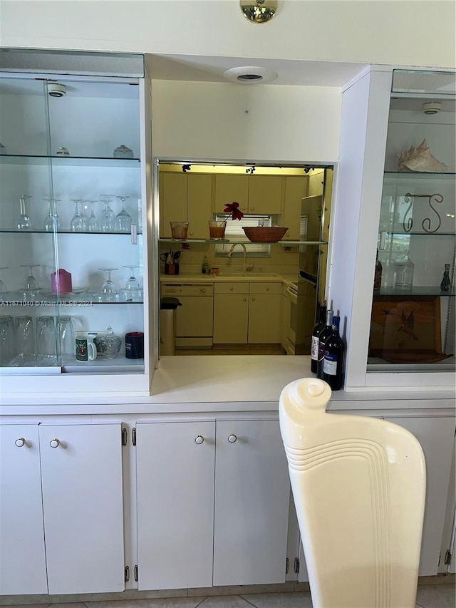 interior space with white dishwasher, white cabinetry, and light tile patterned floors