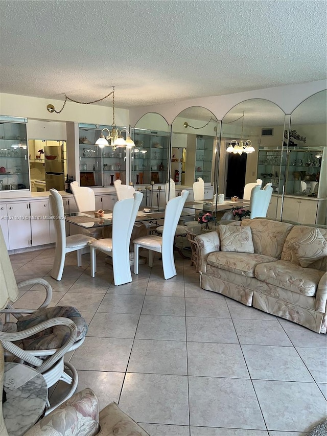 interior space with an inviting chandelier, a textured ceiling, and tile patterned flooring