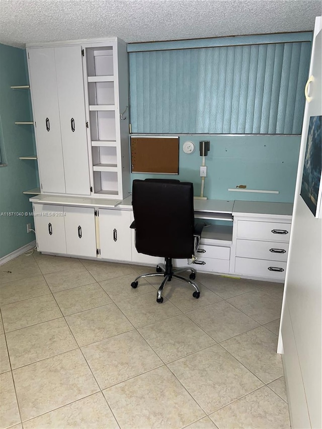 tiled office space featuring a textured ceiling and built in desk