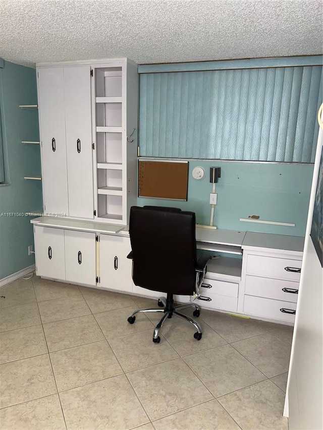 home office with built in desk, a textured ceiling, and light tile patterned floors