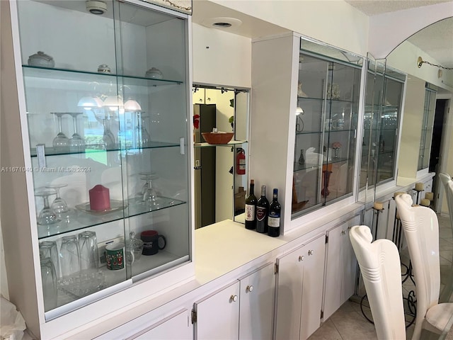 bar with light tile patterned floors and white cabinets