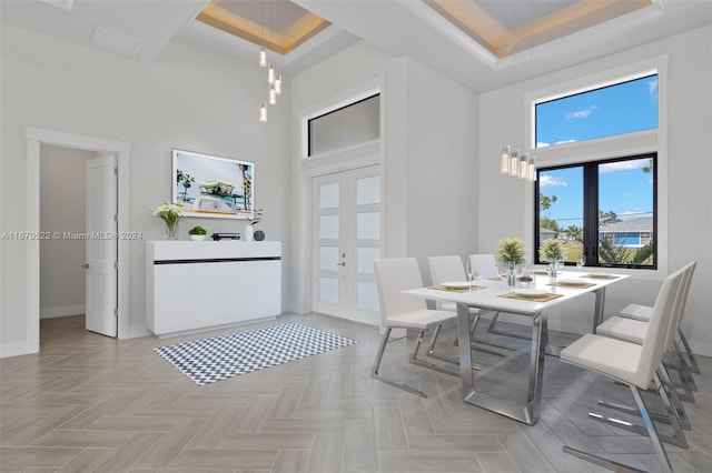 dining room featuring french doors, a raised ceiling, a towering ceiling, and light parquet flooring