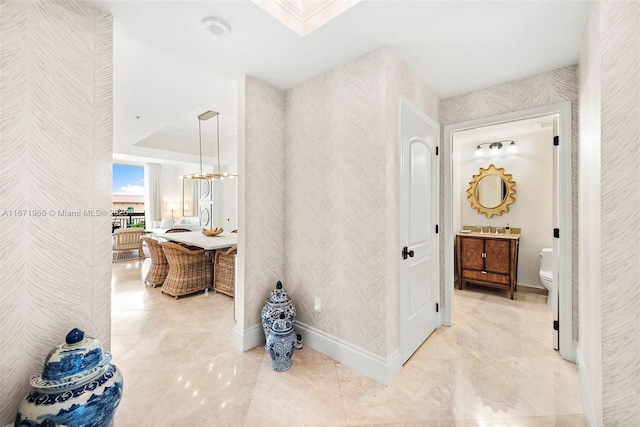 corridor with a tray ceiling and baseboards